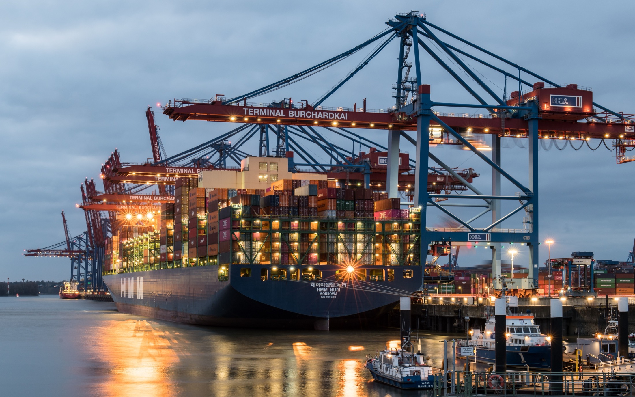 Container ship under terminal cranes in evening light